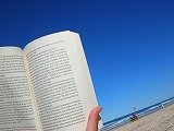 青い空の下違国の本を読む写真